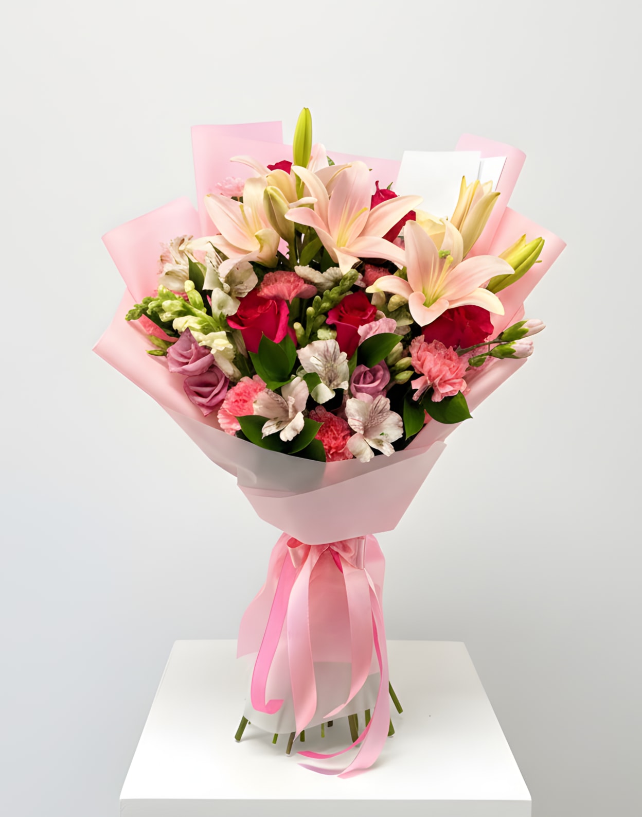 Bouquet of pink lilies and mixed roses wrapped in pink paper