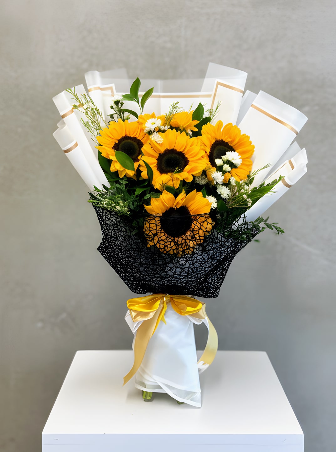 Bouquet of sunflowers wrapped in white and black paper with a yellow ribbon