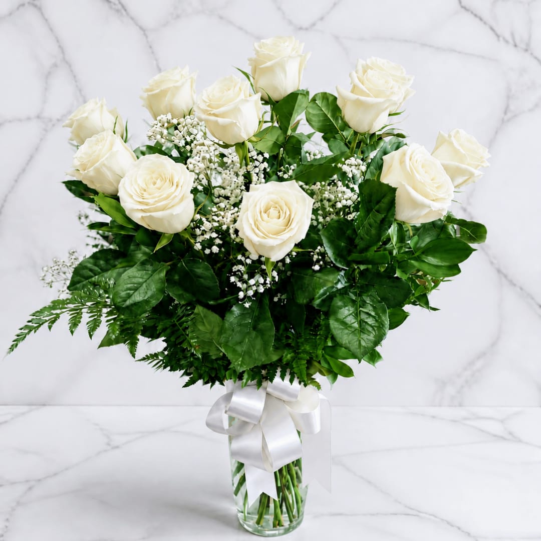 White roses in a clear glass vase with a white ribbon