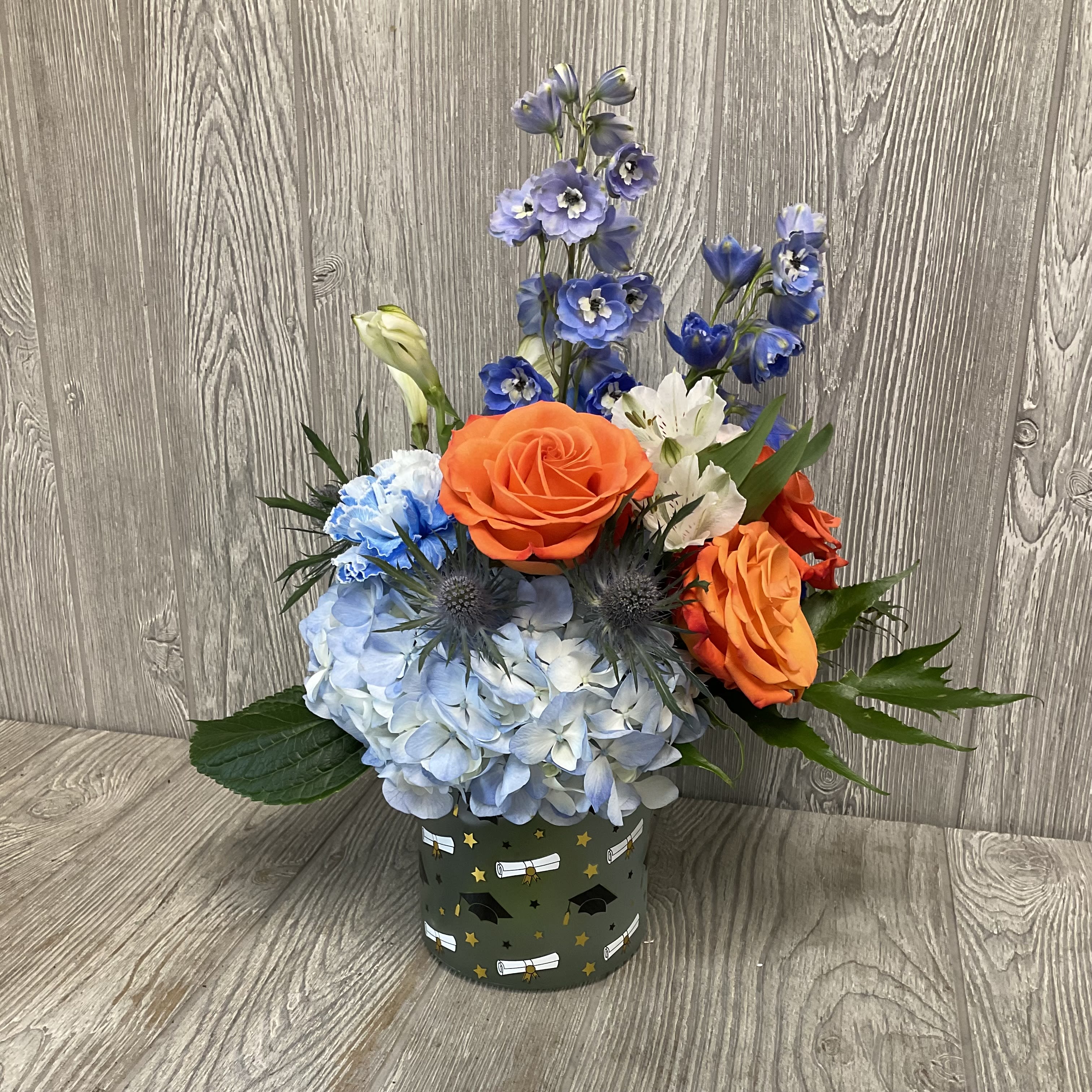 Blue hydrangea and orange roses in a decorated container