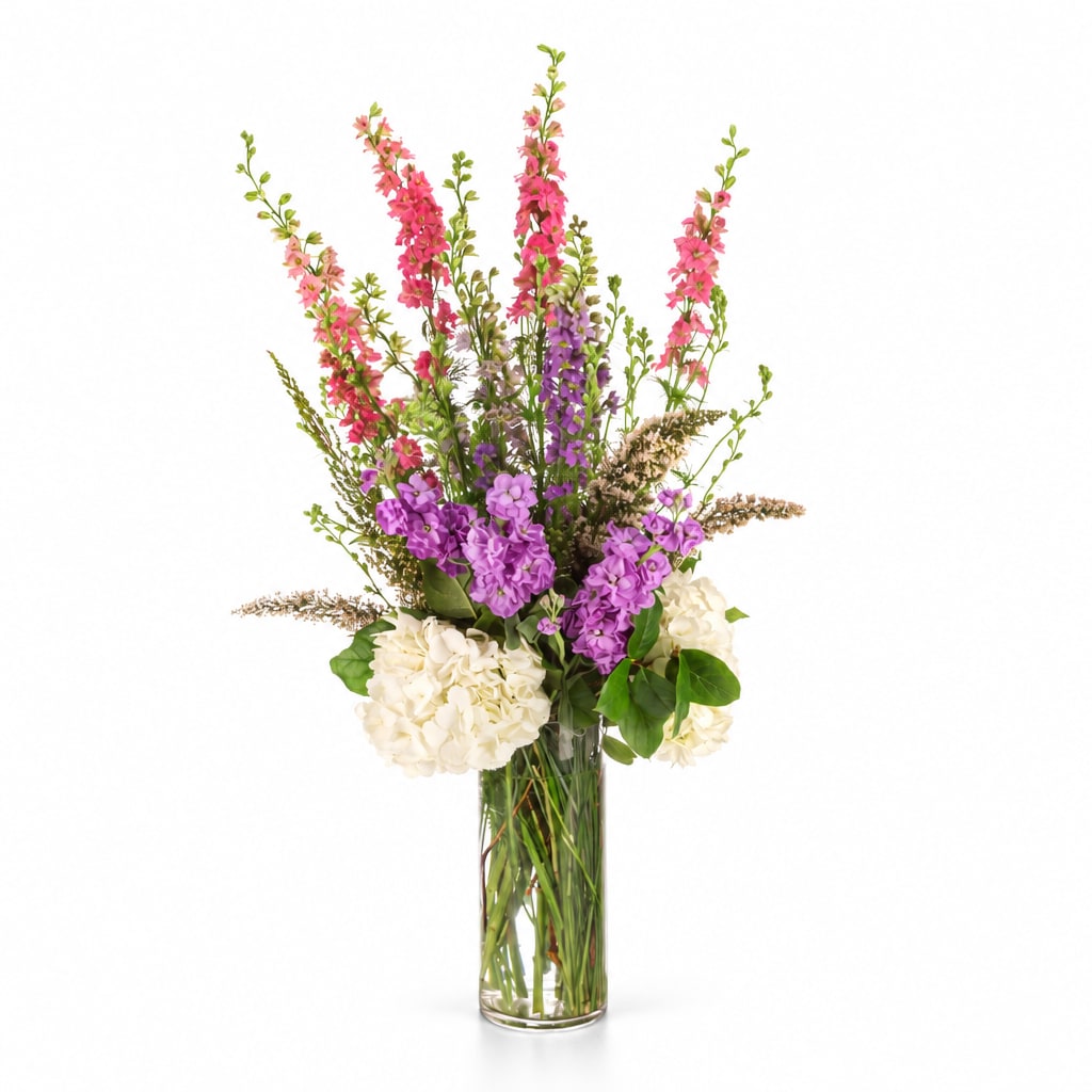Tall bouquet of pink and purple flowers in a clear glass vase