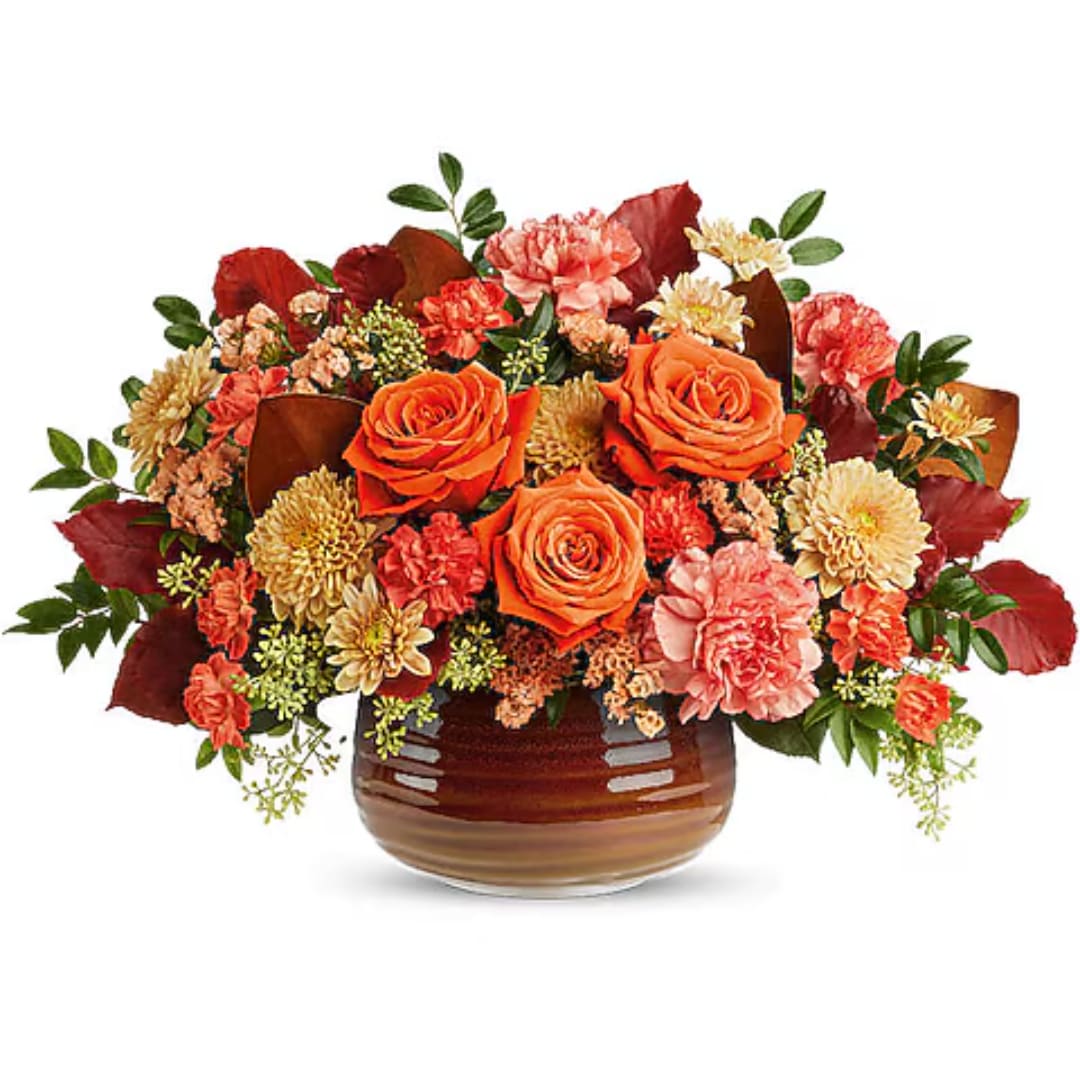 Orange roses and mixed fall flowers in a brown glass vase