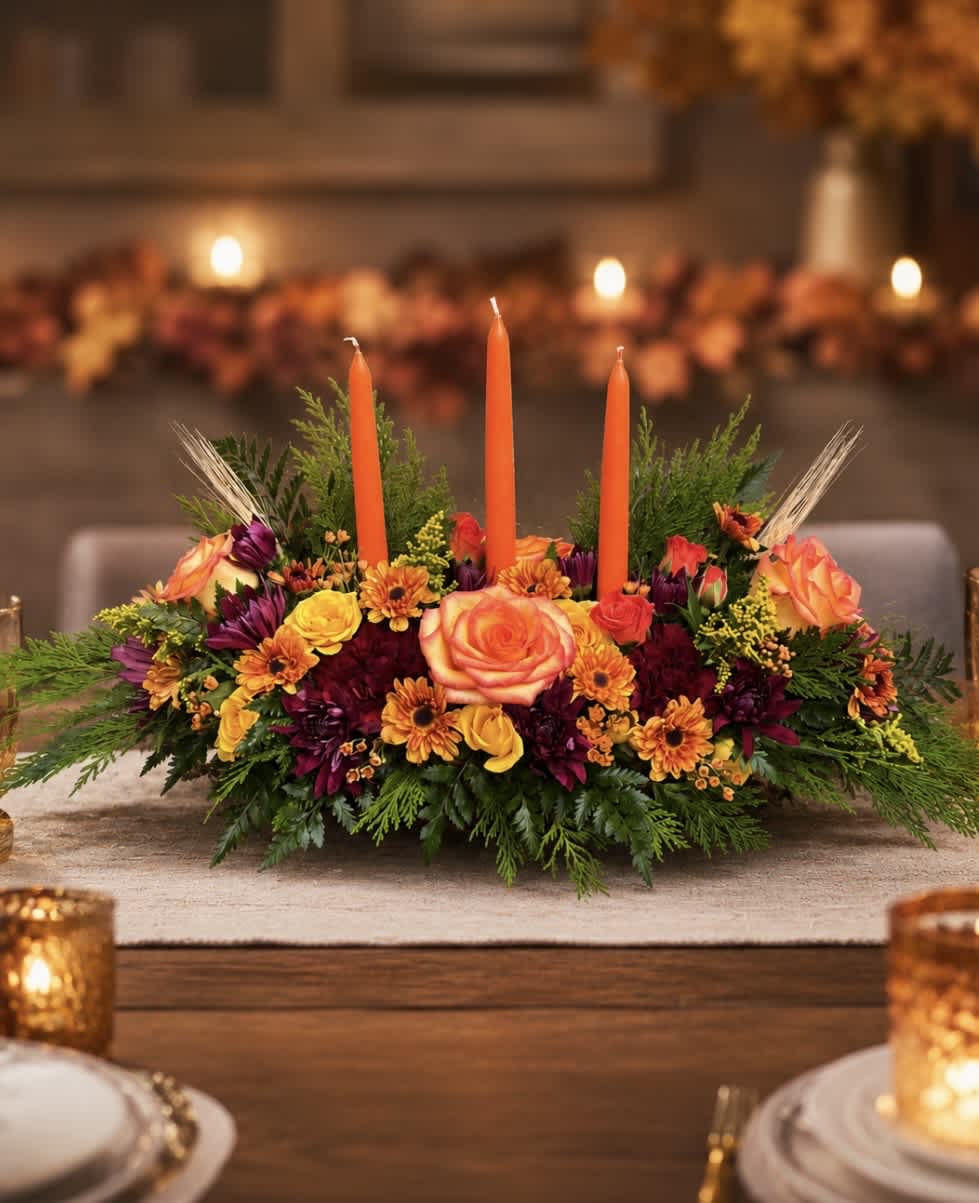 Low floral centerpiece with orange candles and mixed autumn blooms