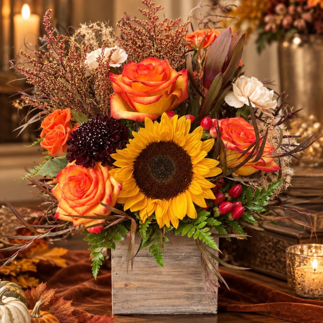 Orange roses and a sunflower in a wooden box arrangement