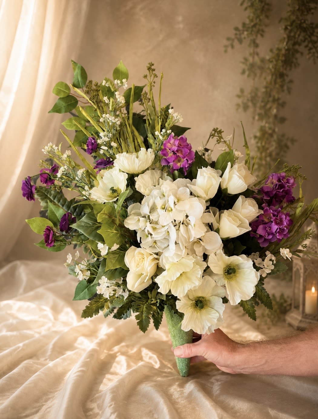 (Silk) Sugarplum - A concentrated cloud of crisp white blooms-hydrangeas and anemone-like flowers-forms the heart of this silk flower arrangement, punctuated by saturated purple accents and soft pink roses for a refined pop of color. Perfect as a sympathy bouquet or a celebratory arrangement for anniversaries and special moments, the vertical stems and broad greenery give it an upward, formal silhouette that feels both substantial and graceful.  Made with lifelike silk anemones, hydrangeas, roses and mixed fillers, the piece pairs airy white sprigs and tall, branching greens to create texture and depth against the purple highlights. Choose the tall ceramic vase for a ready-to-display focal arrangement, or select the wrapped-hand bouquet version for a hand-held presentation-either option presents a garden-fresh, elegant statement that will make the recipient feel truly seen. Vase not included 