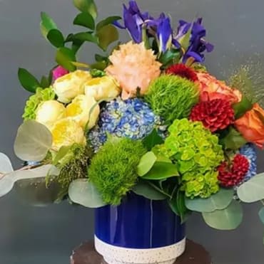 Colorful mixed flower arrangement in a blue ceramic vase