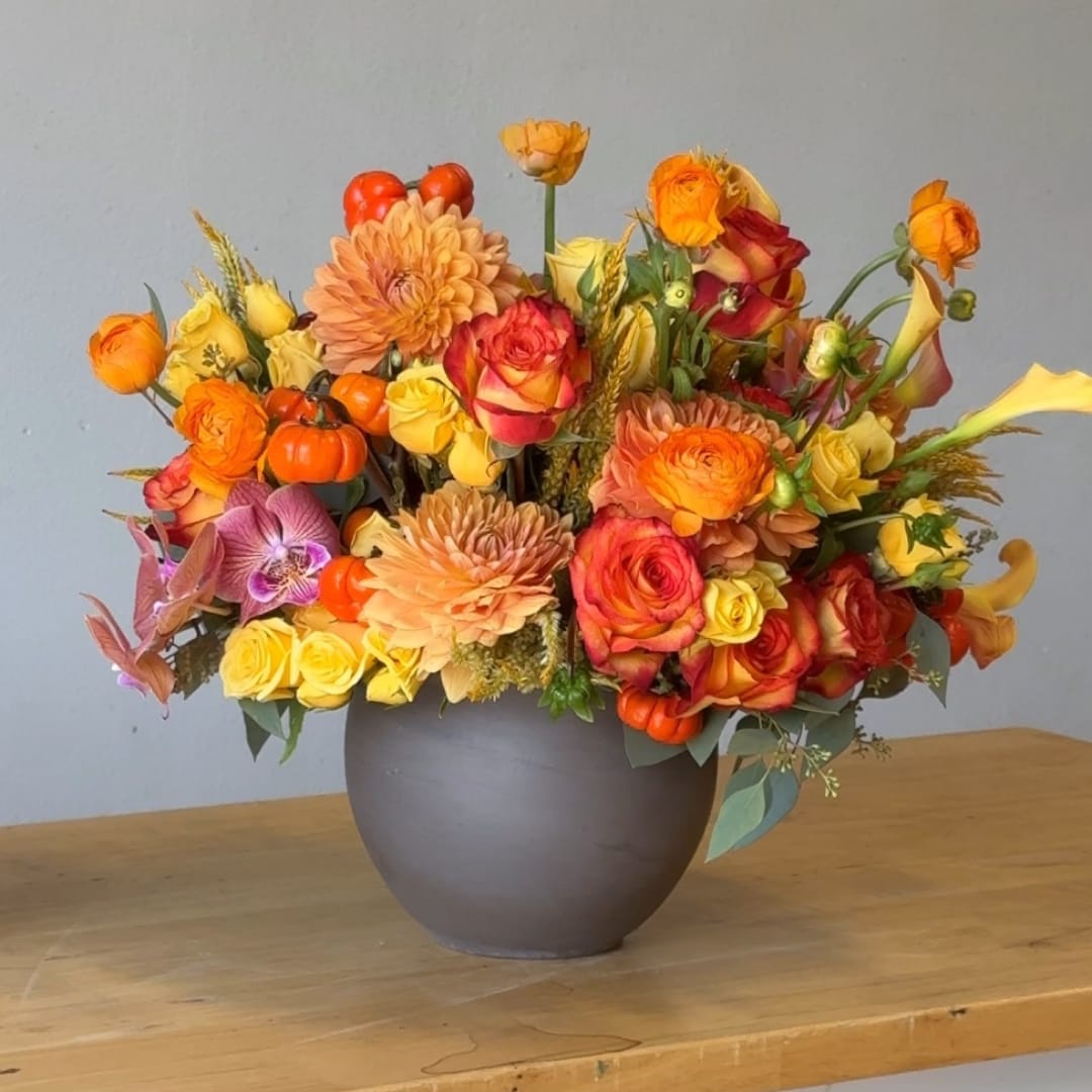 Orange and yellow floral arrangement in a gray vase