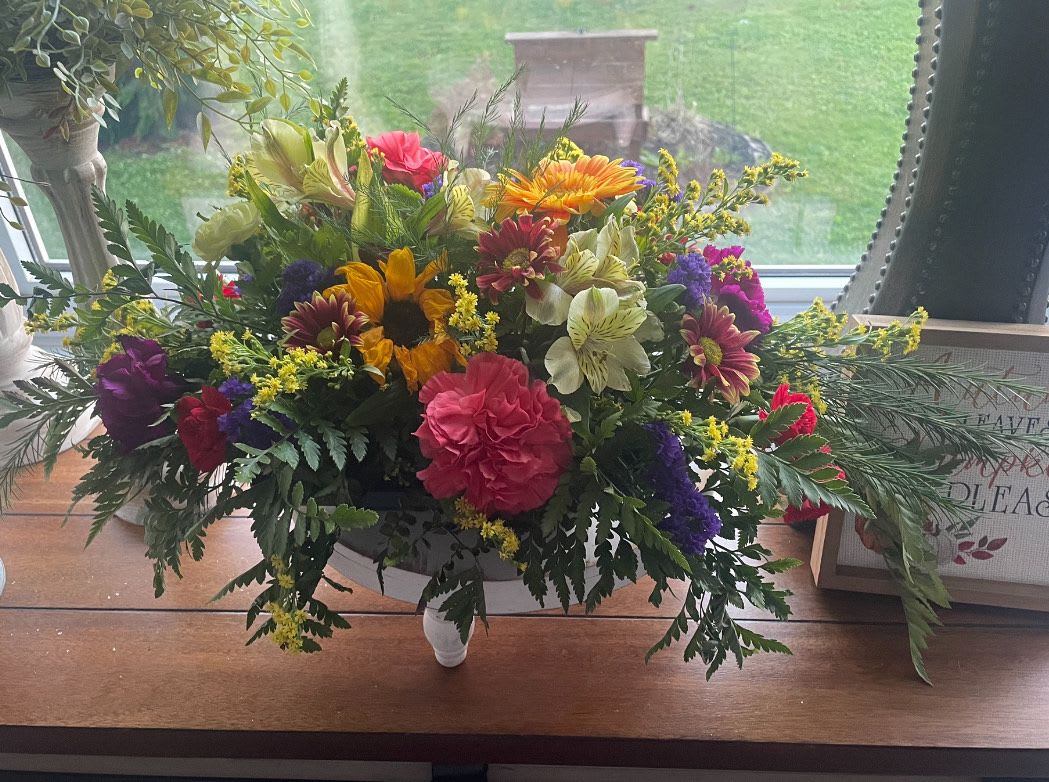 Mixed bouquet in a white pedestal bowl with sunflowers and carnations