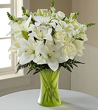 White lilies and roses in a green glass vase