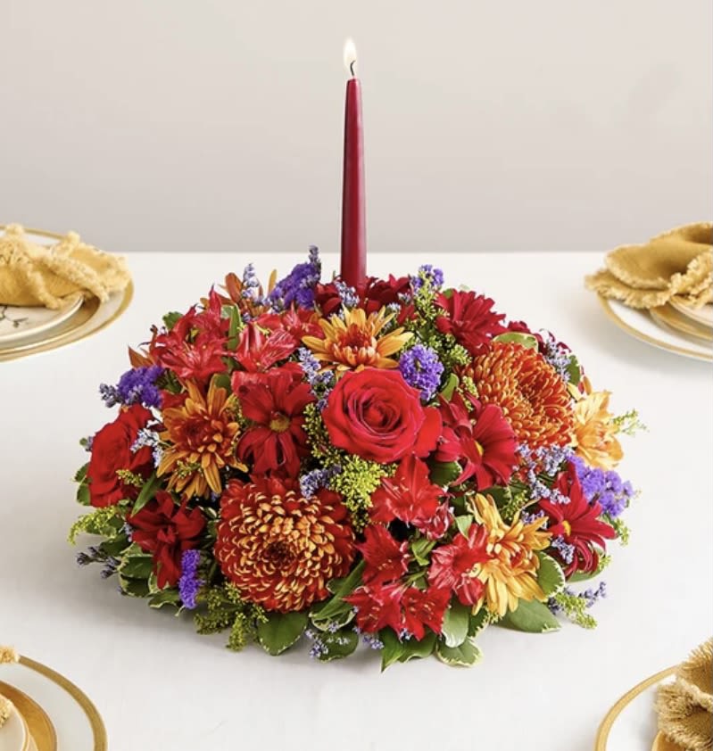 Brilliant autumn centerpiece  - Set the table in brilliant style. Our centerpiece captures the rich beauty of autumn, with bursts of red, bronze, and purple amid assorted greenery. A burgundy taper candle stands at the center, ensuring a warm and welcoming ambience for every gathering.