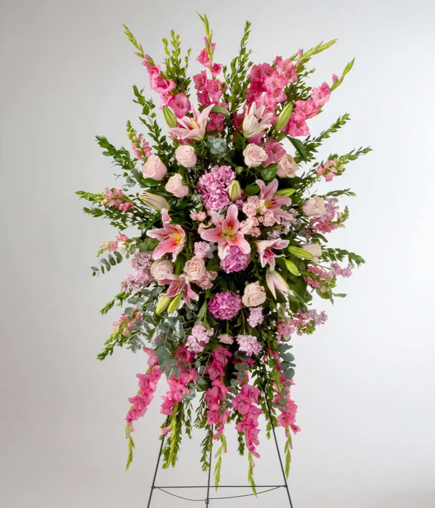 Full Compassion  - Pink roses, lilies, and more come together for a blushing pink standing funeral spray. A beautiful and elegant display for the beloved. Different combinations can be requested.  This arrangement is appropriate to send to the funeral home or service.  For color modifications, please indicate in the "instructions" section of your order.