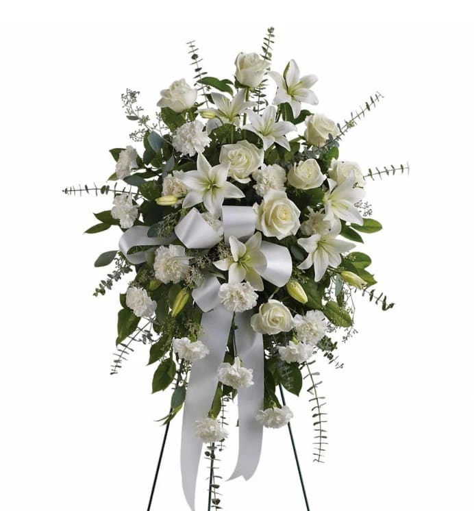 White floral standing spray with lilies, roses, and ribbon