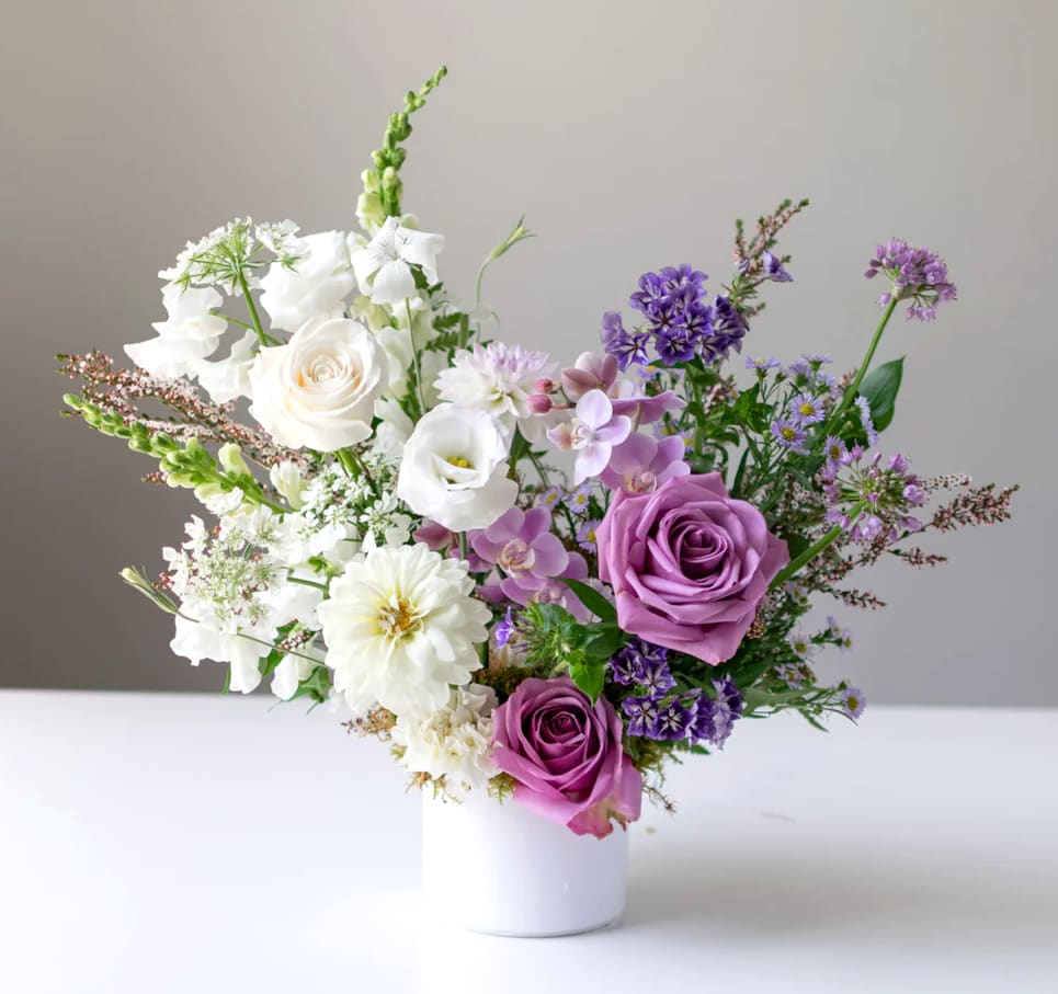 Purple and white mixed bouquet in a white vase