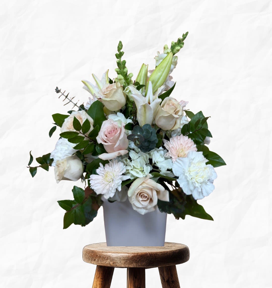White and blush floral arrangement in a gray vase