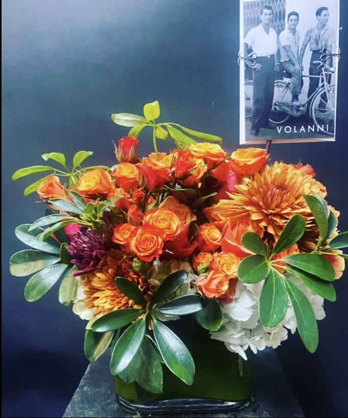 Orange roses and chrysanthemums arranged in a square glass vase