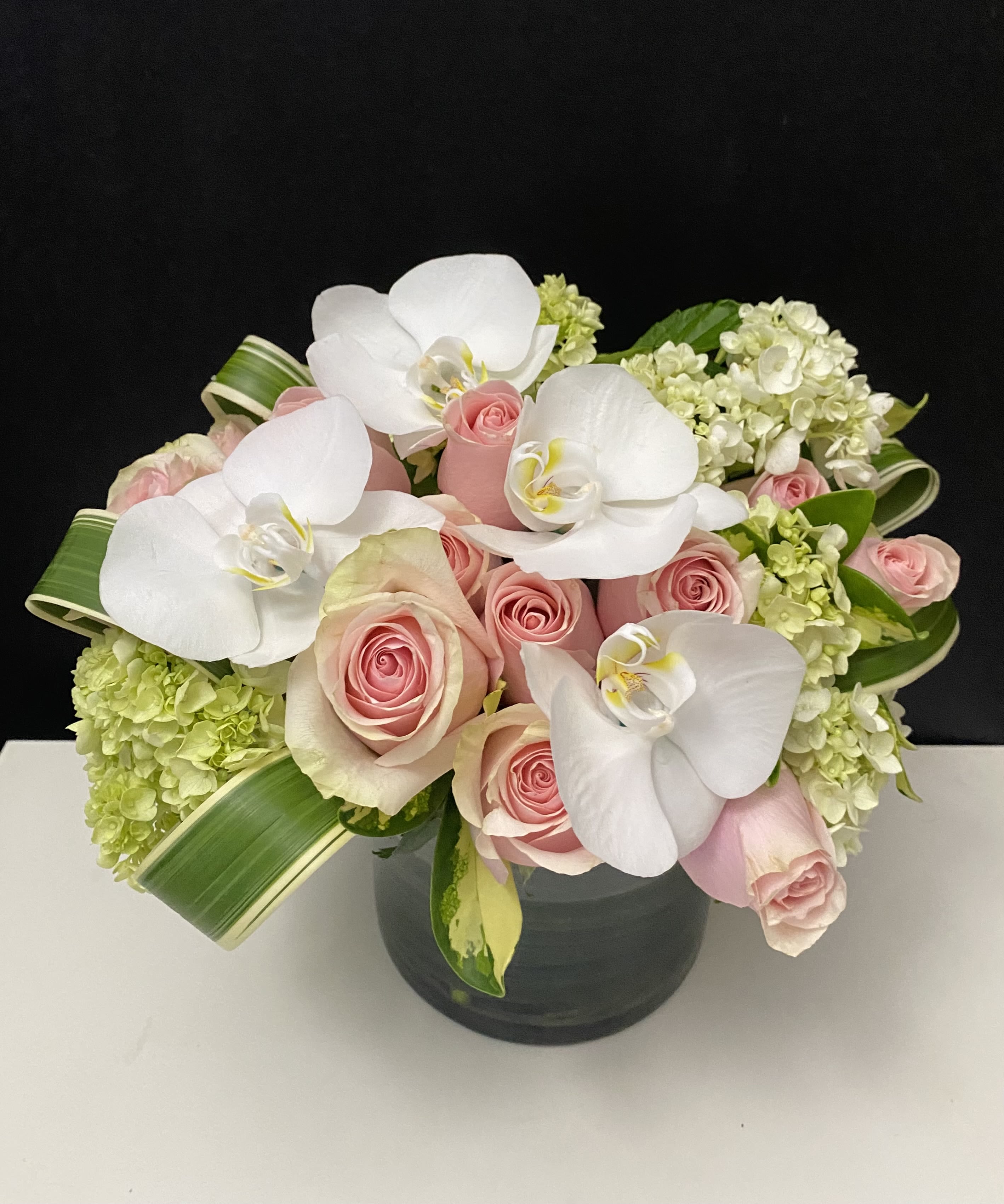 Pink roses and white orchids in a dark vase