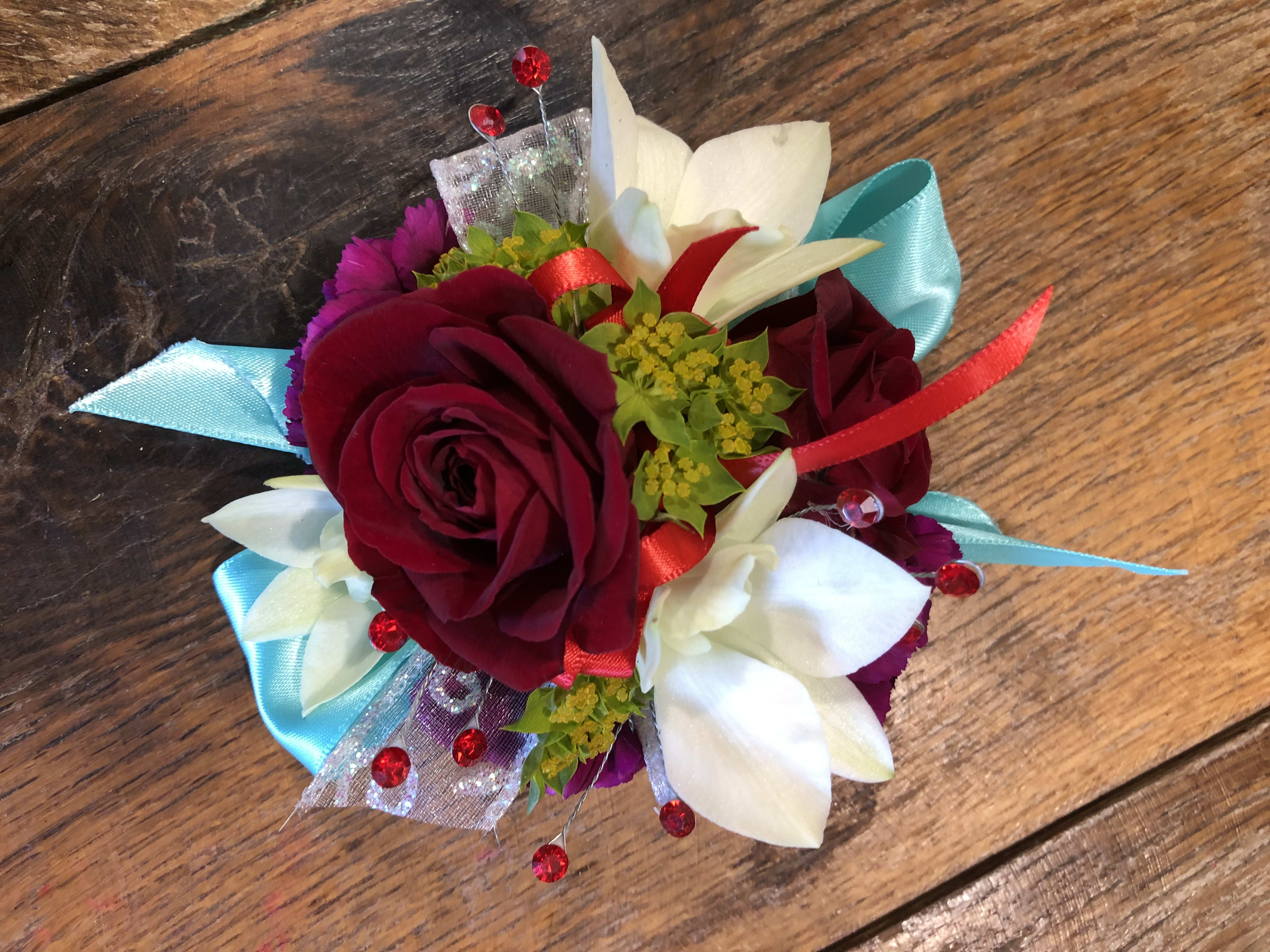 Small corsage with red roses and white flowers on blue ribbon