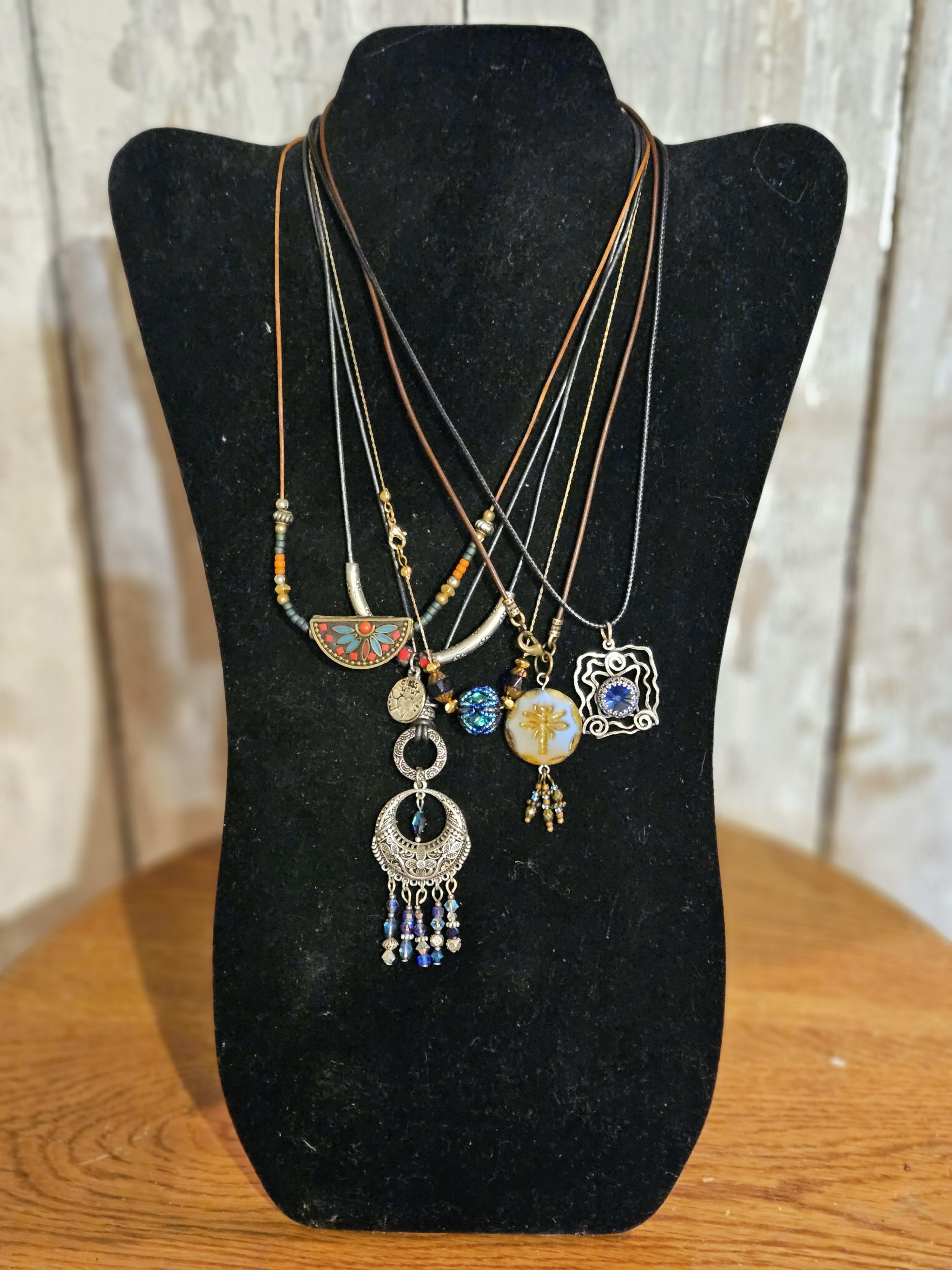Layered pendant necklaces on a black display bust