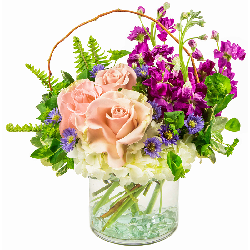 Spring Garden - Lush, inviting, and inspired by nature in full bloom, Spring Garden is one of our most beloved floral designs. This arrangement features soft white hydrangeas paired with vibrant hot pink stock, romantic pink roses, and delicate purple Monte Casino asters. Fresh green bupleurum, curly willow, and sword fern add natural texture and movement, creating a garden-inspired look that feels effortless and full of life.  Spring Garden is a versatile favorite—perfect for birthdays, anniversaries, celebrations, thank-you gifts, or simply brightening someone’s day. Its balanced blend of color, greenery, and natural elements makes it a beautiful choice any time of year.