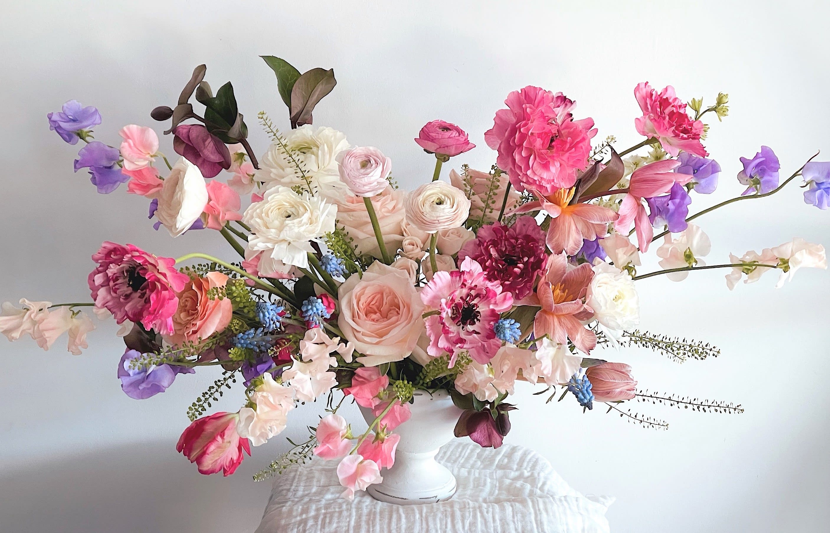 Pastel floral arrangement in a white vase with pink, purple, and white blooms