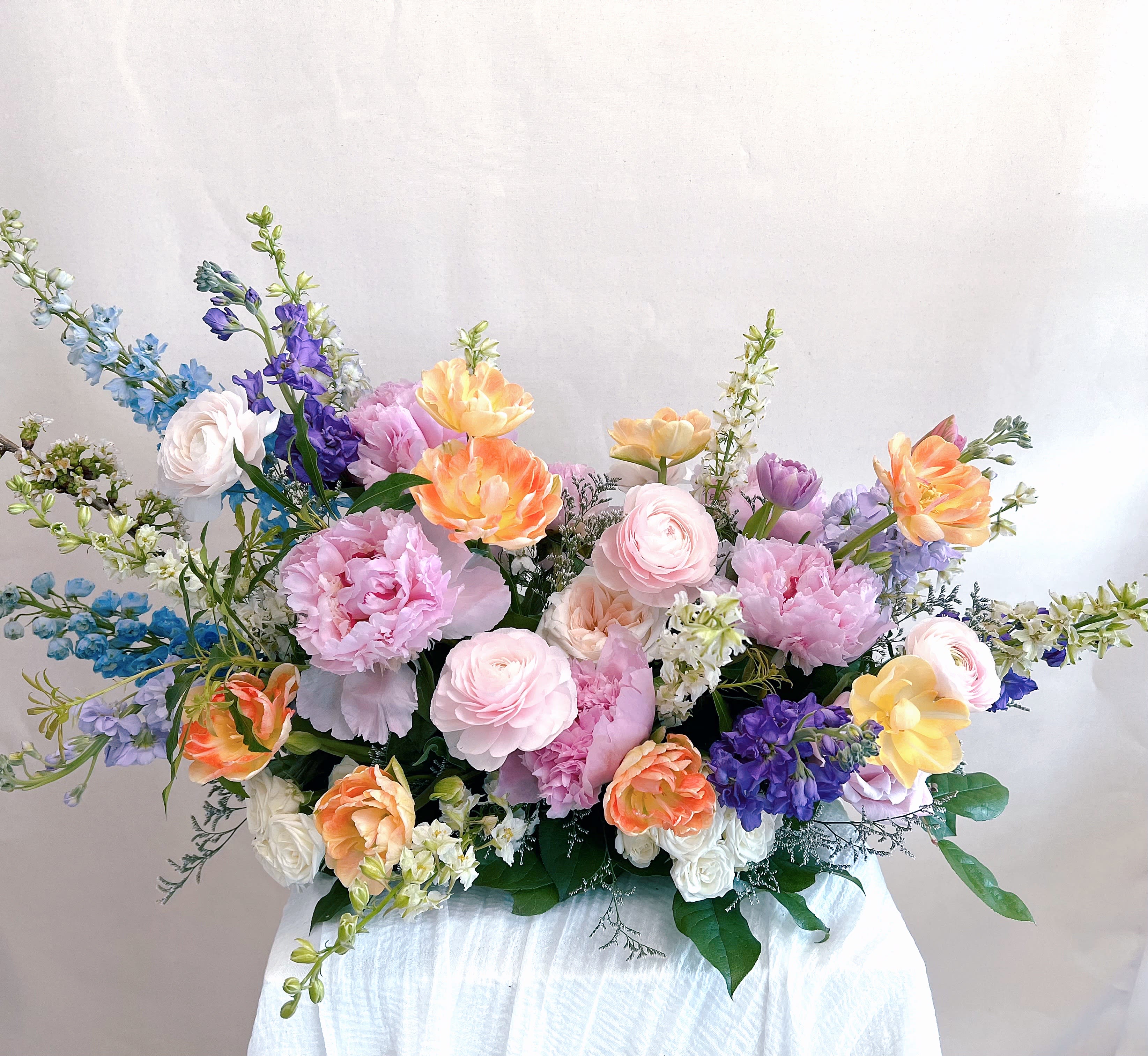 Favorite Child - A showstopping display of spring's best pastels.  The blooms used may vary by the season and availability, and since each arrangement is custom-made to order by our talented designers, they will all look slightly different, which is what makes them so special!  The photo is a representation of the overall vibe of this Botanique signature arrangement. 