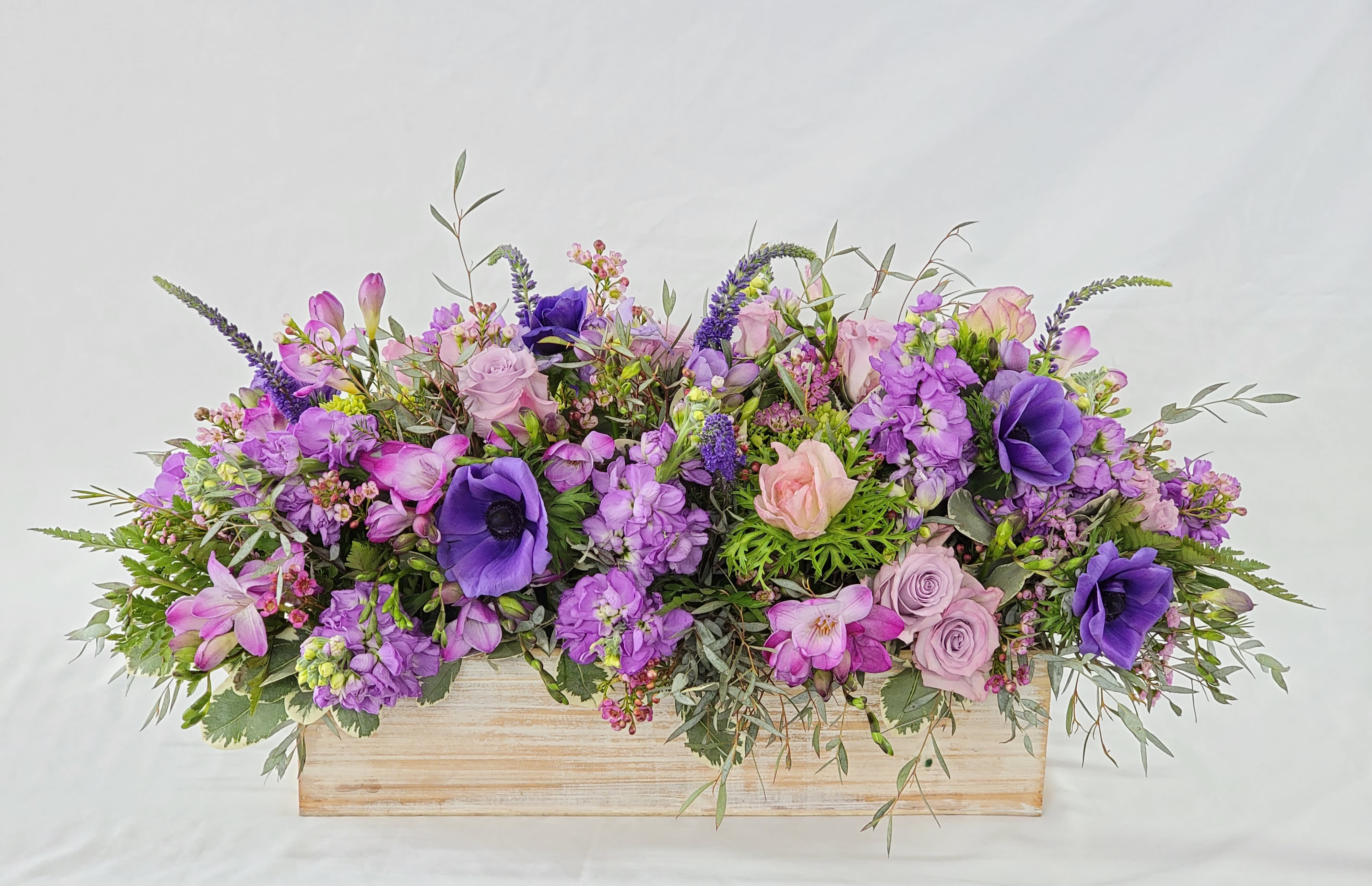 Purple and pink floral arrangement in a wooden box