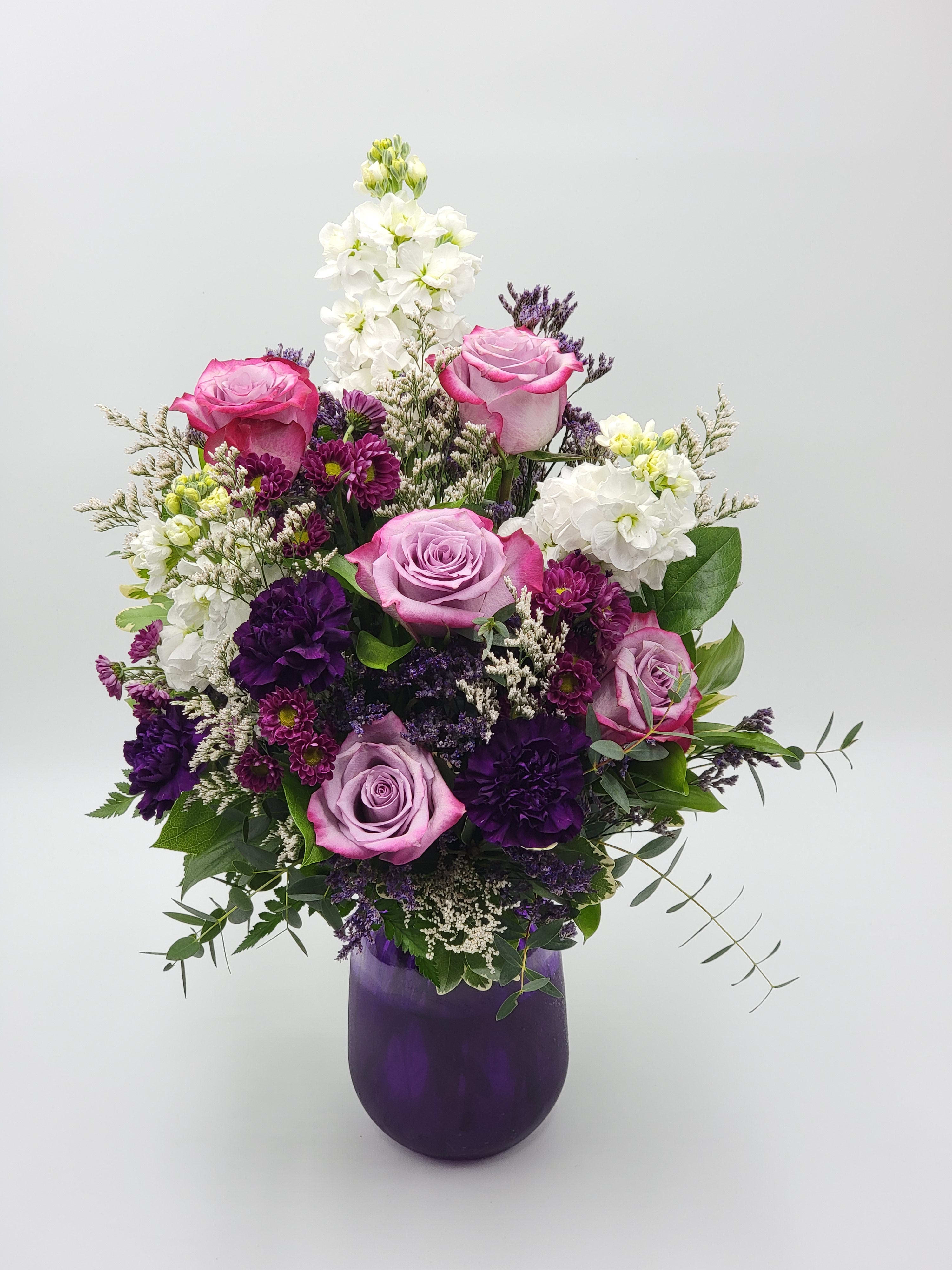 Violet Dream  - This violet arrangement is a jewel toned beauty! Flowers include, carnations, roses, stock, and tulips in a purple vase.   Roughly 20" tall and 12" wide