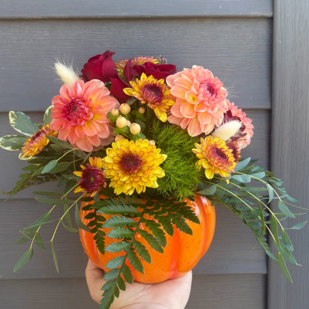 Fall bouquet in an orange pumpkin vase with pink and yellow flowers