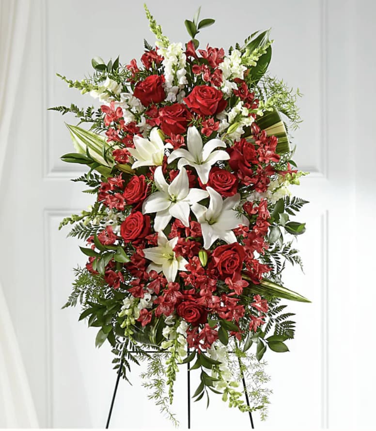 Standing floral spray with red roses and white lilies on a black easel