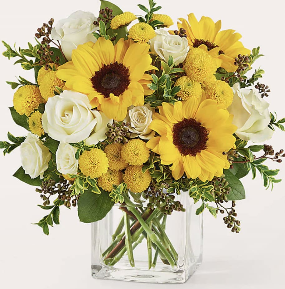 Yellow sunflowers and white roses in a clear glass vase