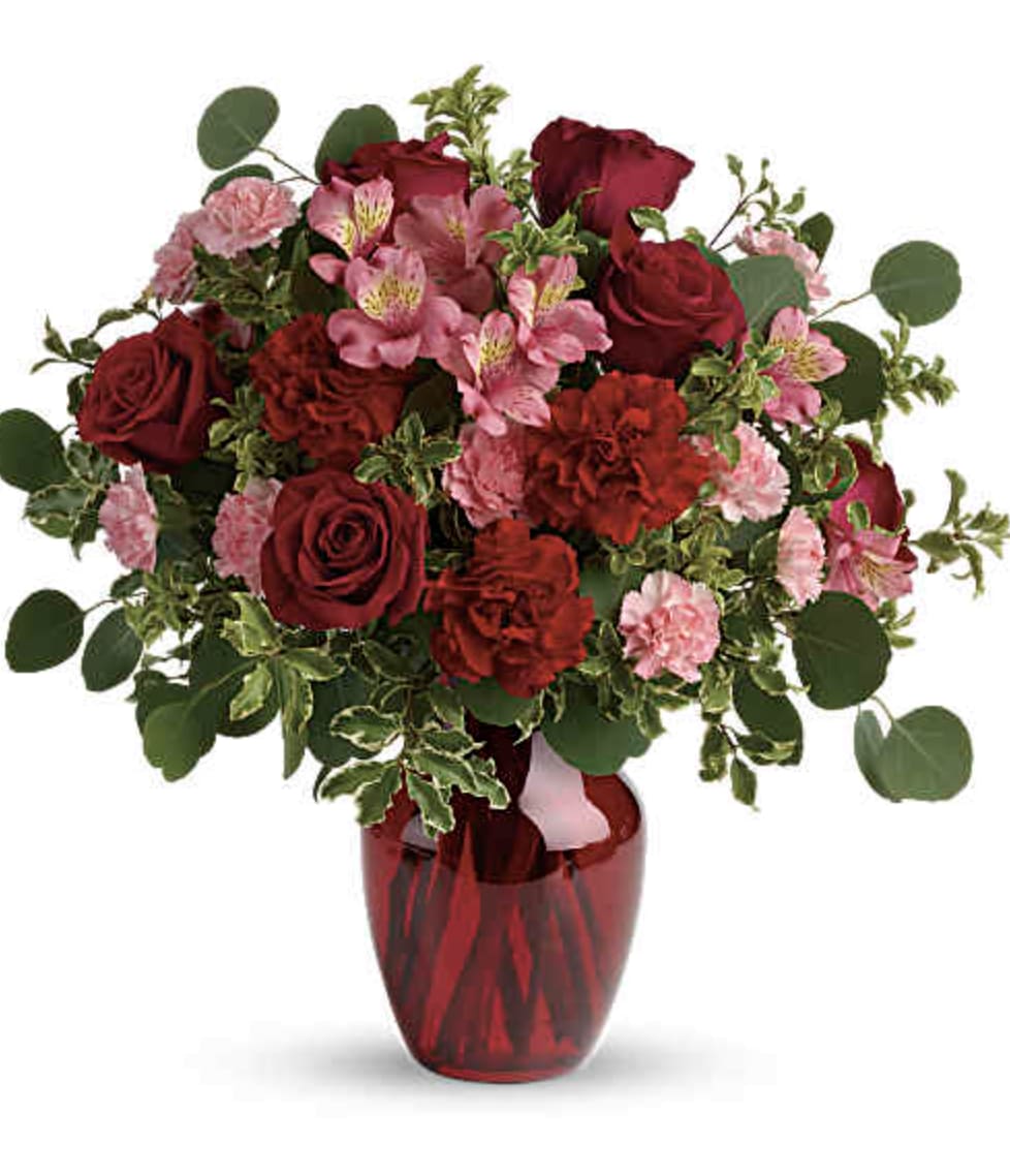Ruby's Red - Fan the flames of love with this sizzling array of red roses and other romantic favorites in a chic ruby red vase. If you want to make a really big impression, surprise her with delivery to her office. Imagine the oohs and ahhs of her co-workers - and her. This gorgeous bouquet includes red roses, red carnations, light pink carnations, with assorted greenery. Delivered in a ruby rose vase.