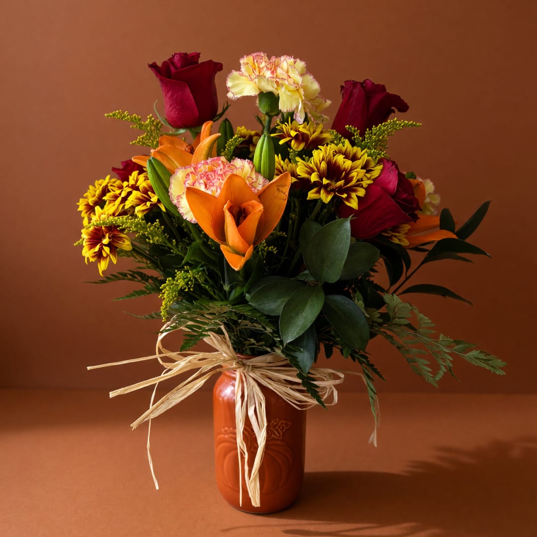 Bouquet of red roses, orange lilies, and yellow chrysanthemums in an orange vase