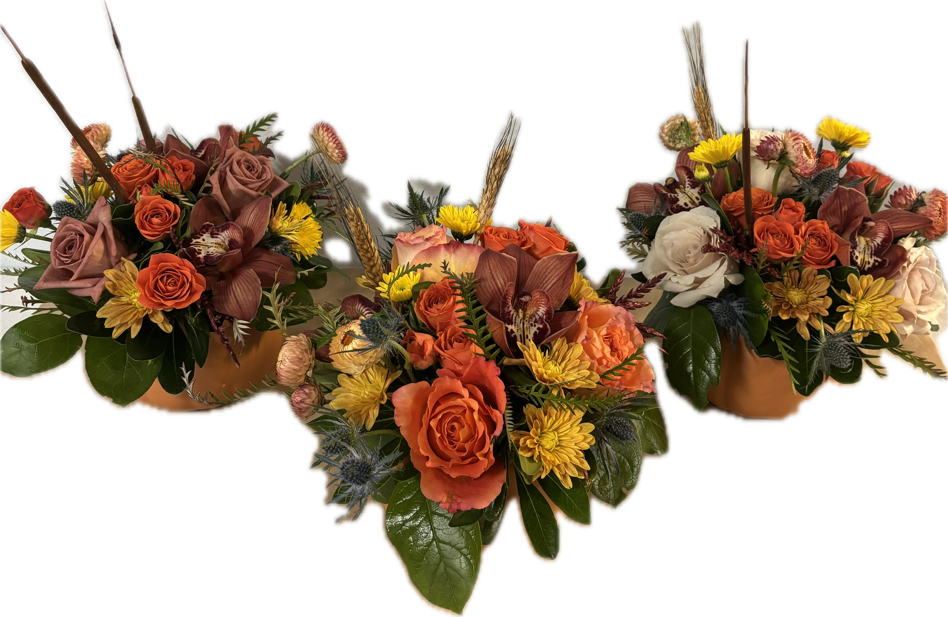 Three autumn floral arrangements with orange and cream roses in low containers
