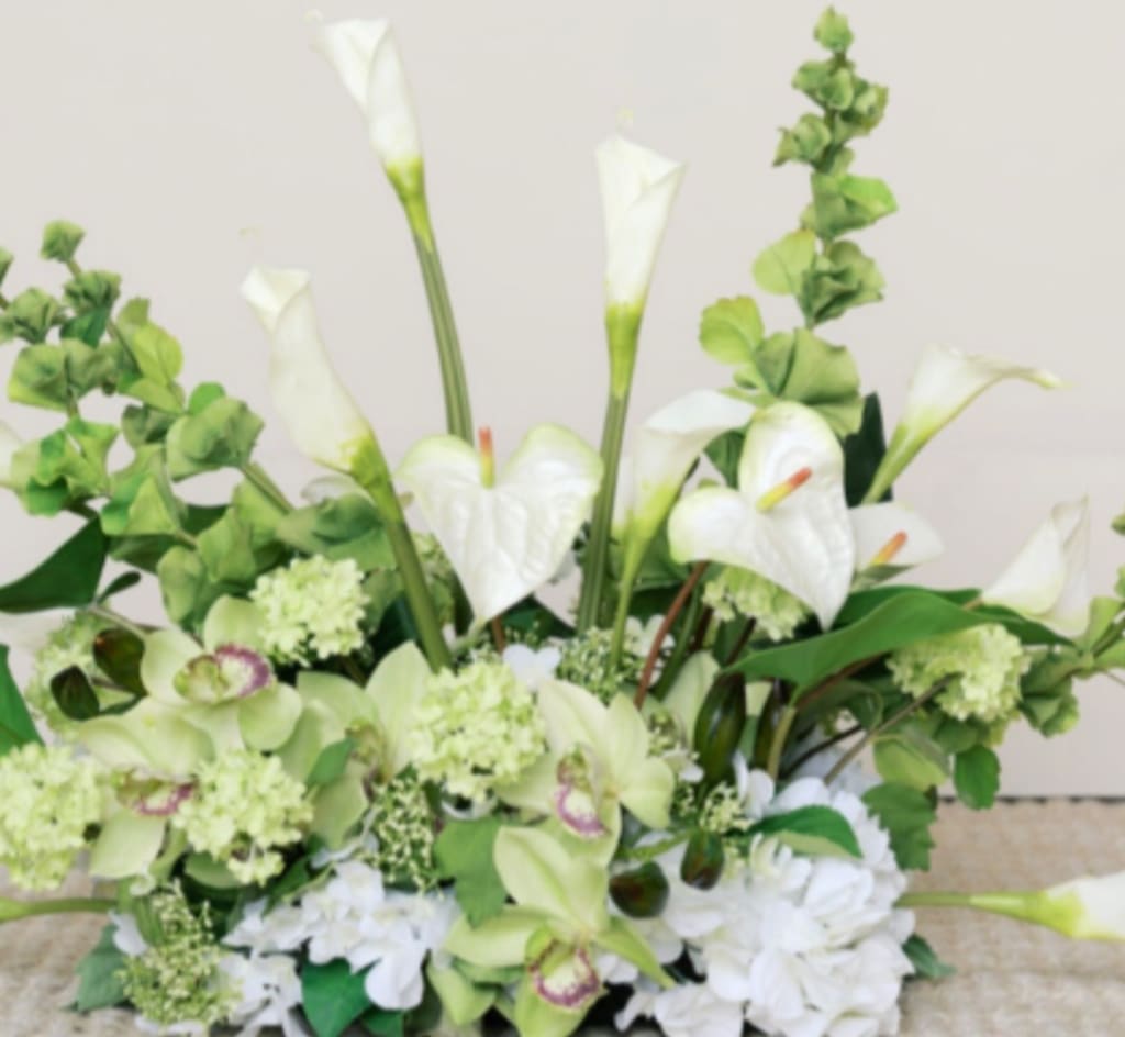 White calla lilies and pale green orchids in a low arrangement