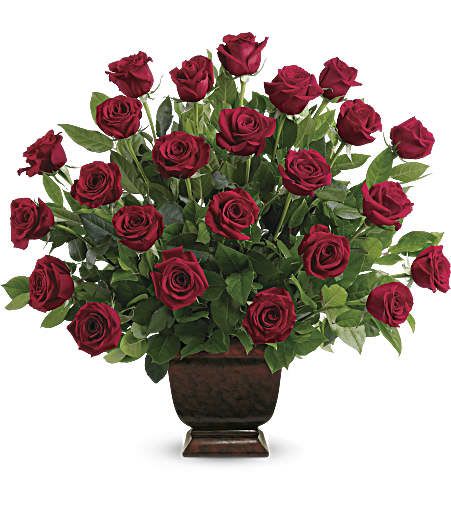 Large arrangement of dark red roses in a brown pedestal vase