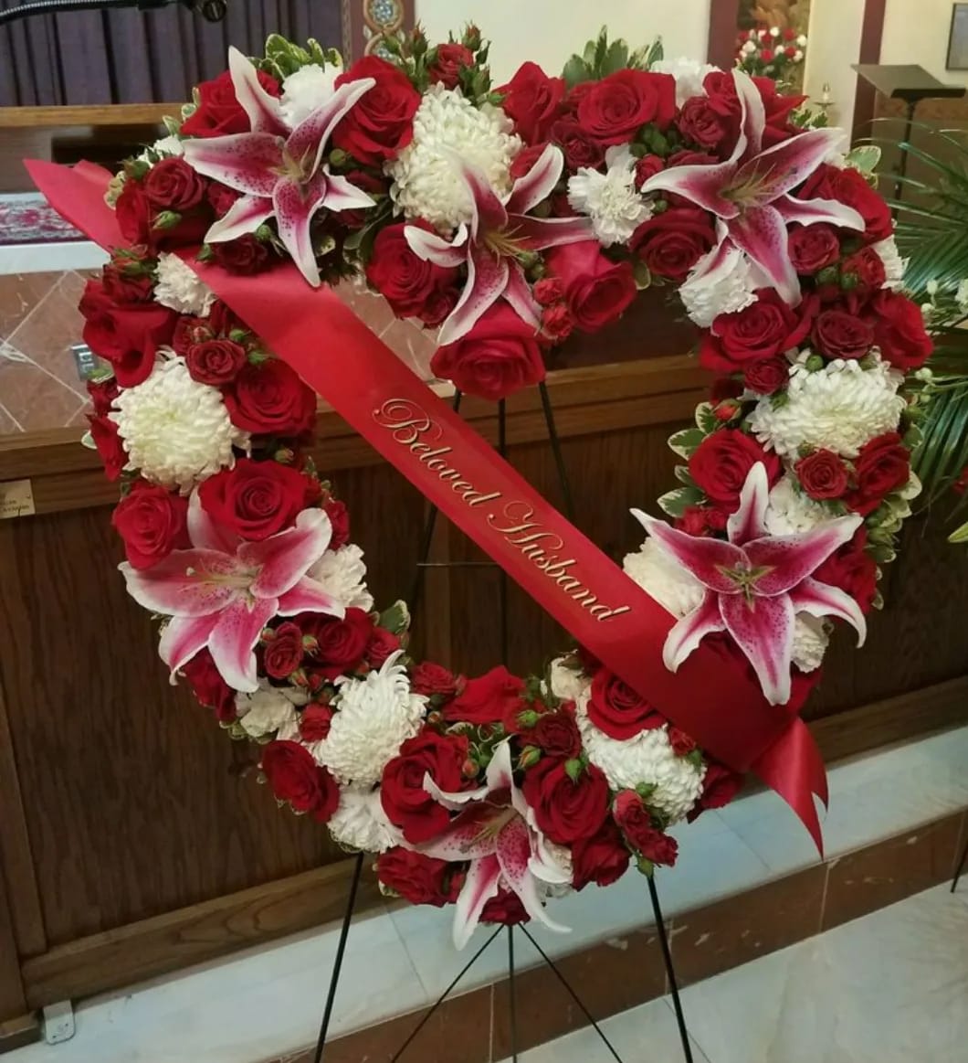 Elegance &amp; Sophistication Open Heart Spray - This elegant 18" open heart wreath is a beautiful expression of love and remembrance. Featuring a graceful combination of roses, stargazer lilies, and football mums, this design symbolizes open-hearted devotion and enduring affection. Expertly arranged on a standing easel, it offers a heartfelt tribute to honor a cherished life with beauty, grace, and dignity.  Please note: Floral variety may vary based on seasonal availability, ensuring each arrangement is fresh and unique.