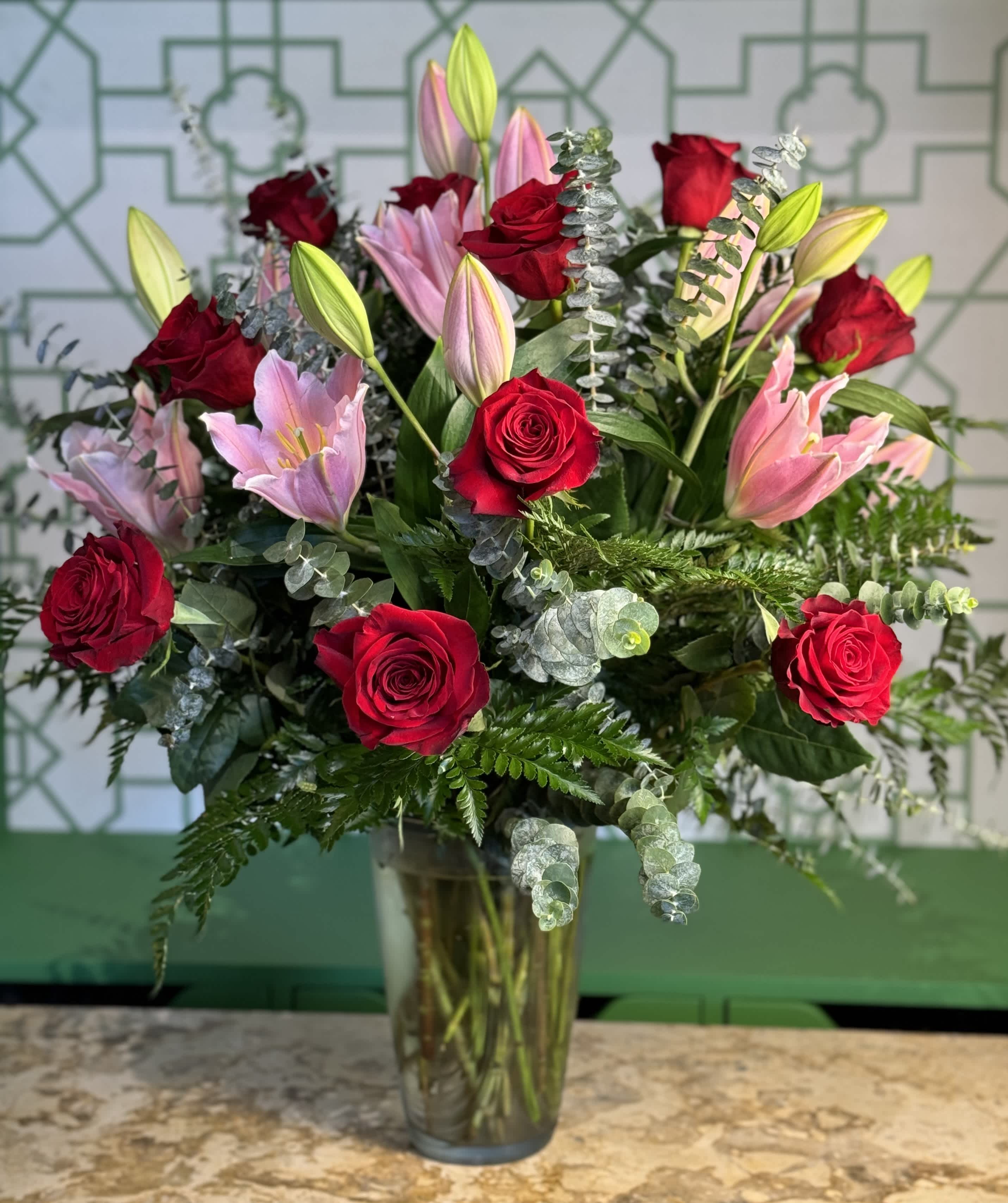 Red roses and pink lilies in a clear glass vase