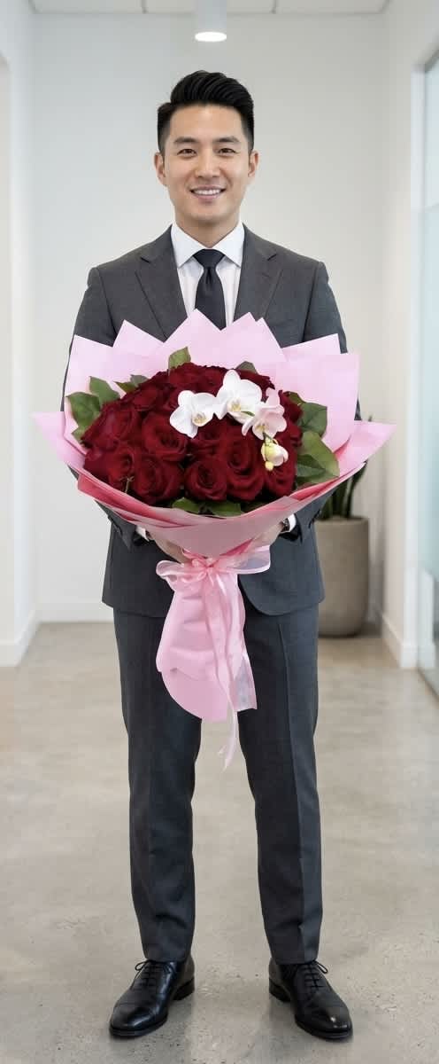 Man holding a bouquet of red roses wrapped in pink paper