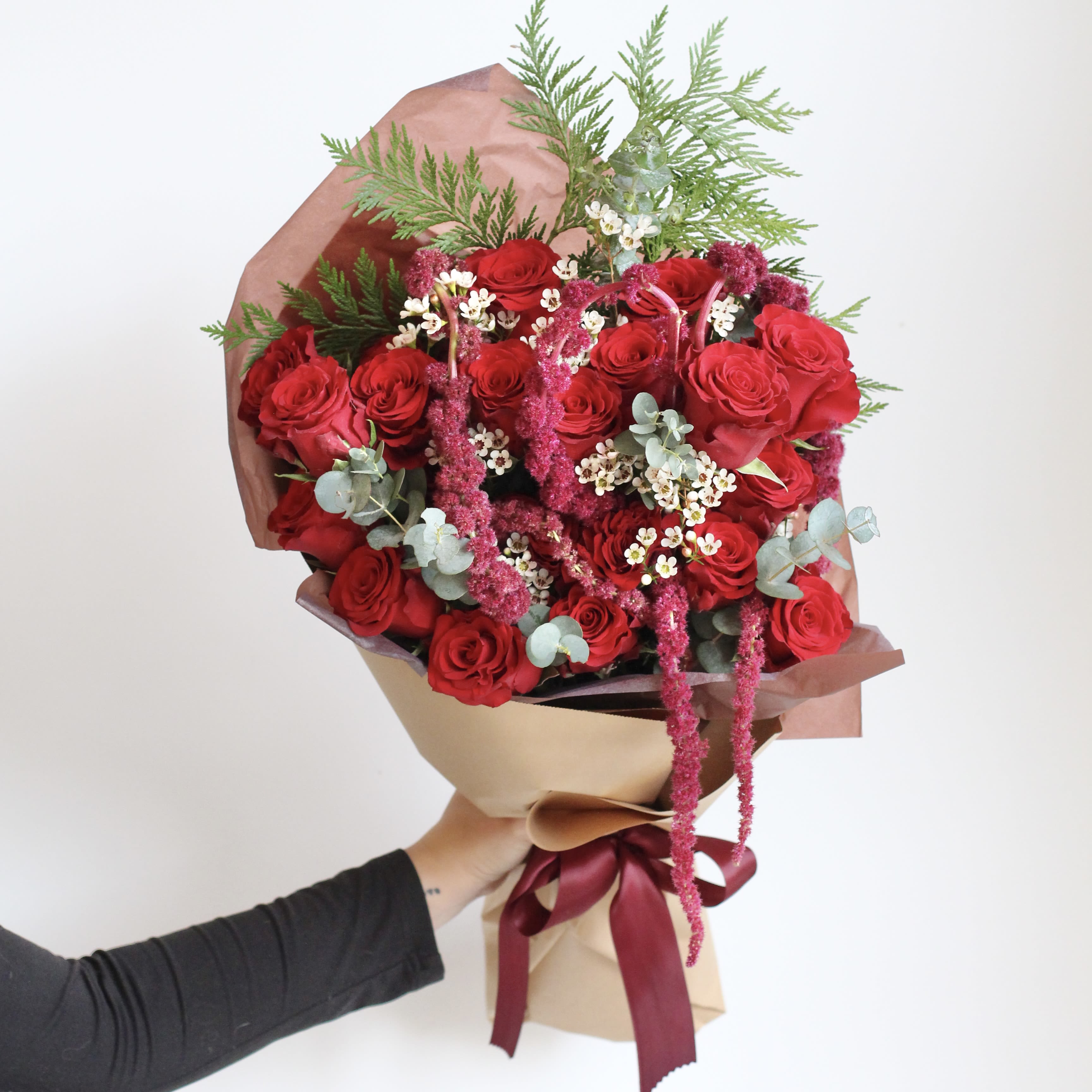 Bouquet of red roses with pink filler and greenery wrapped in paper