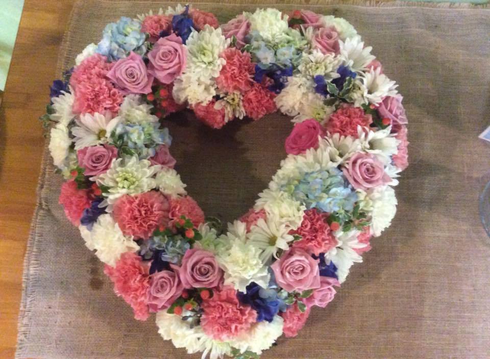 Heart-shaped floral wreath with pink, white, and blue flowers