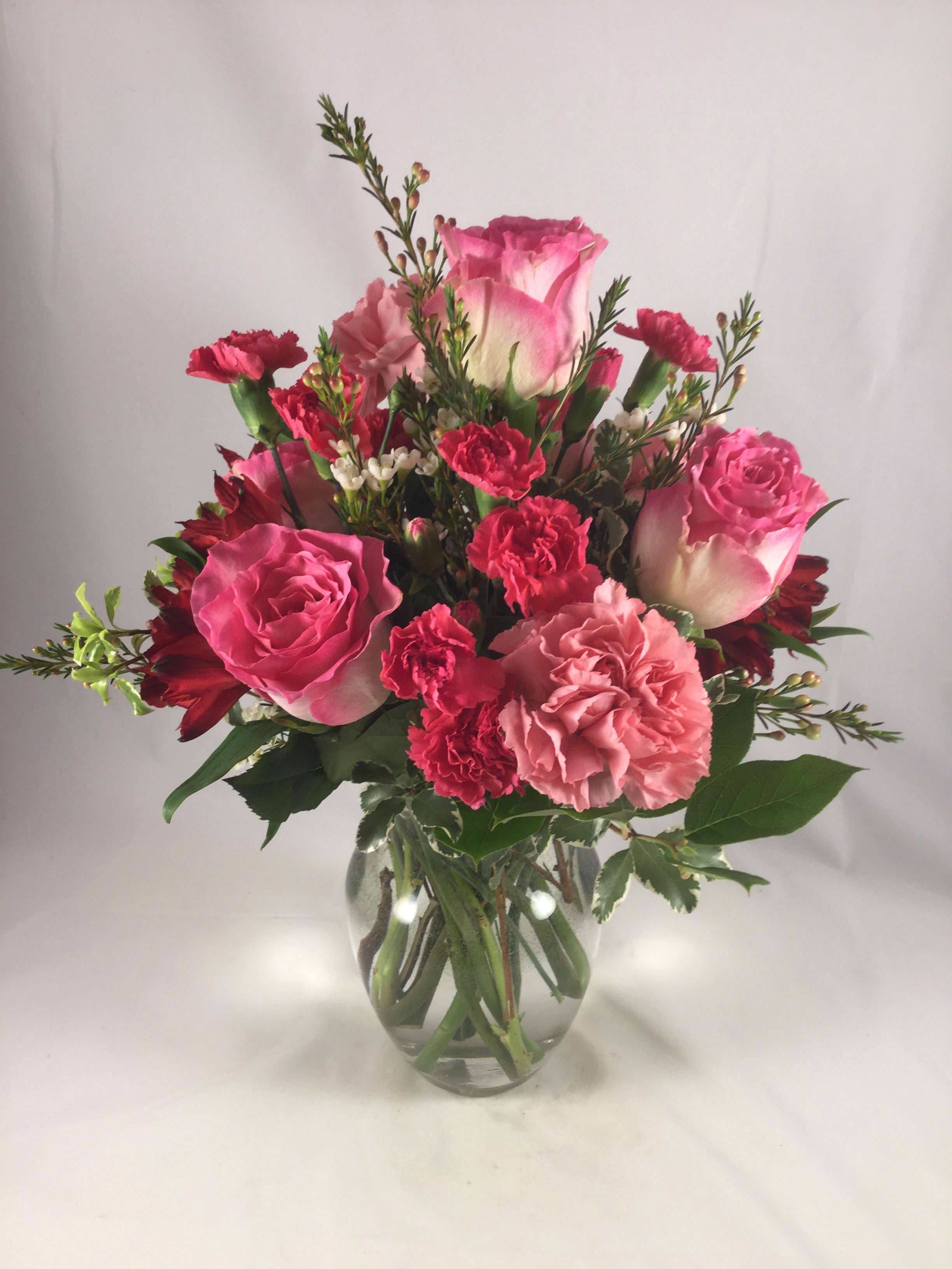 Pink roses and carnations in a clear glass vase