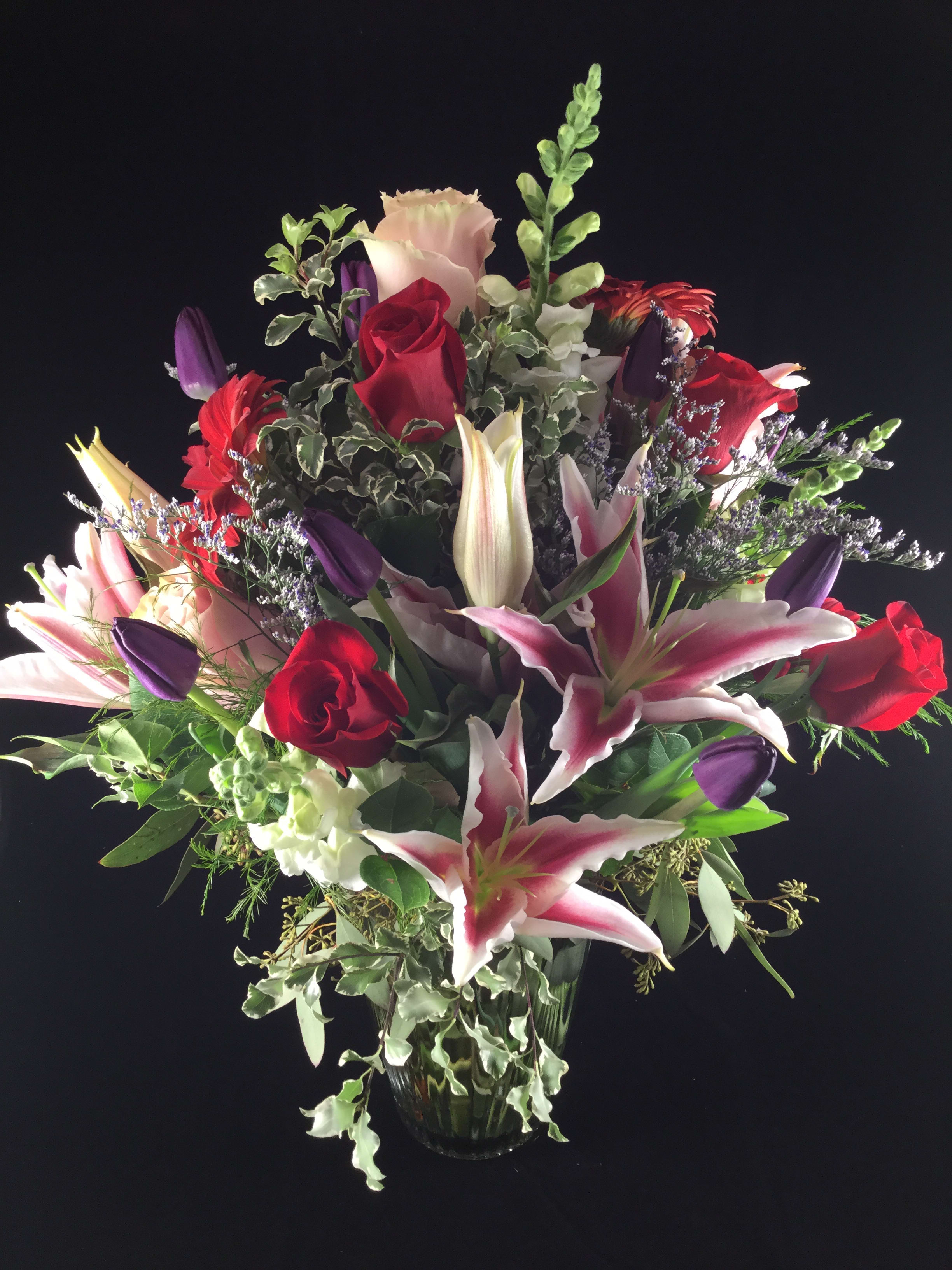 Mixed bouquet of red roses and pink lilies in a glass vase