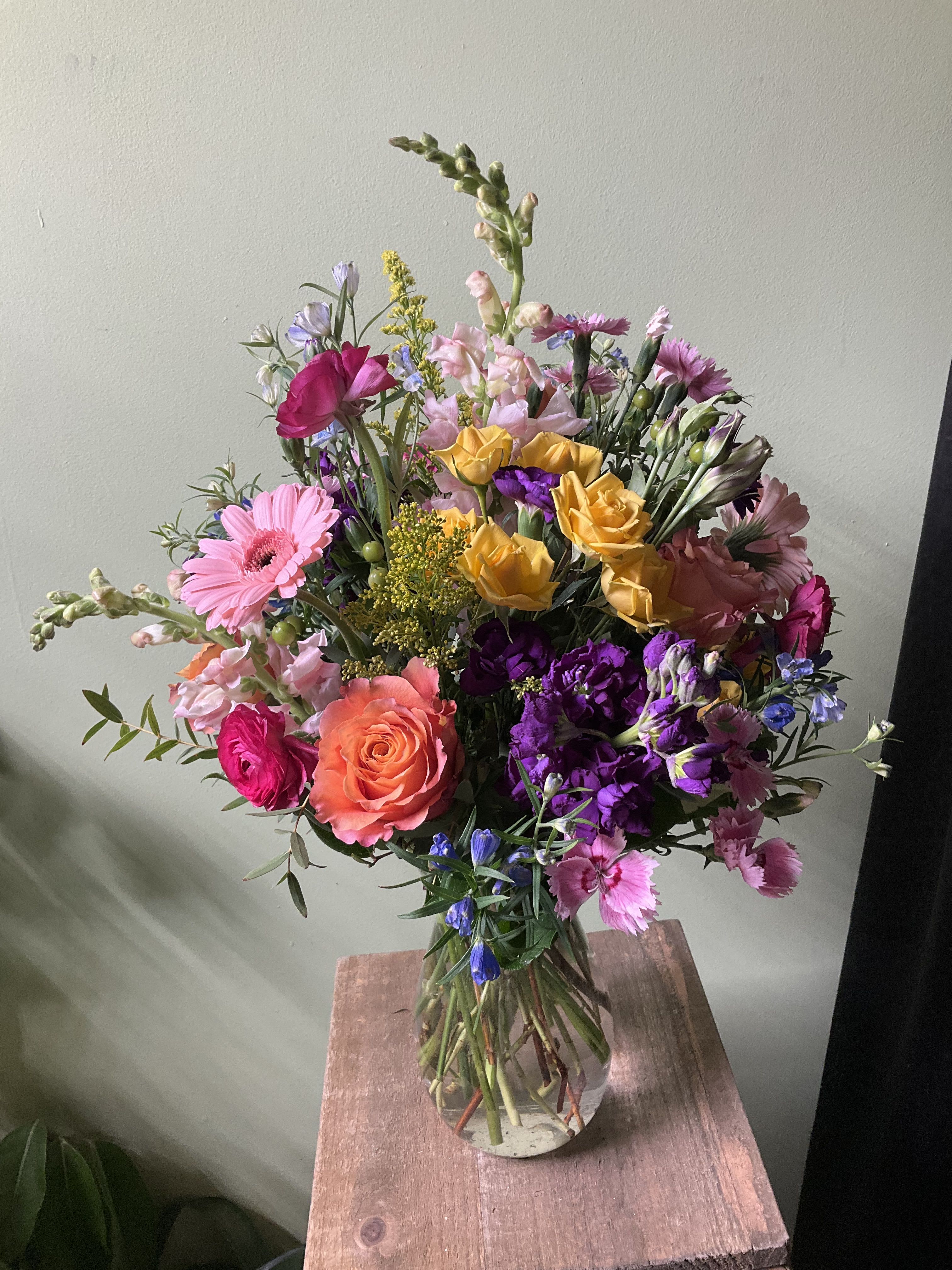 Mixed bouquet of pink, purple, yellow, and orange flowers in a glass vase
