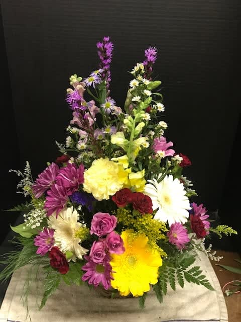 Tall mixed flower arrangement with daisies, roses, and lilies in bright colors