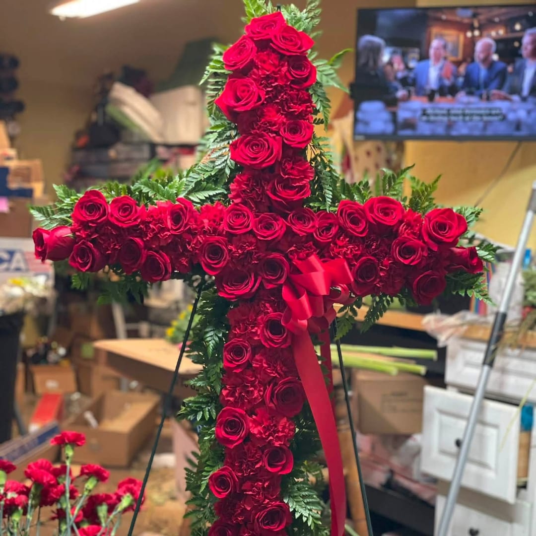 Red rose cross with a ribbon, displayed on a stand