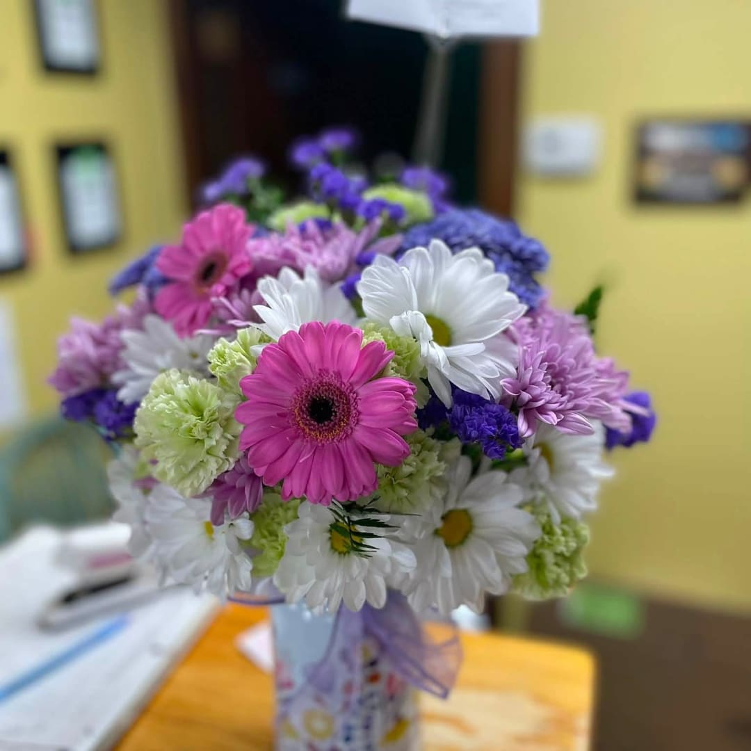 Bouquet of pink, white, and purple daisies in a decorated vase