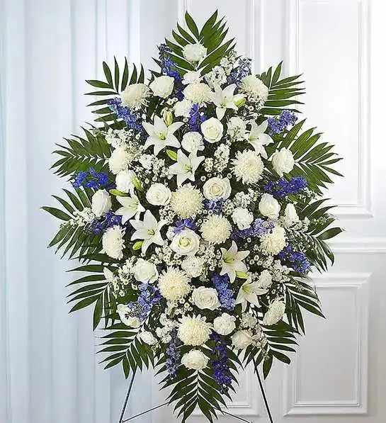 Blue &amp; White Funeral Standing Spray - When someone so dear passes, a standing tribute is a fitting way to pay respects. Our impressive standing spray arrangement, meticulously handcrafted by expert florists with pristine white and rich blue blooms, is a lush, full presentation that makes for a proud and respectful commemoration.