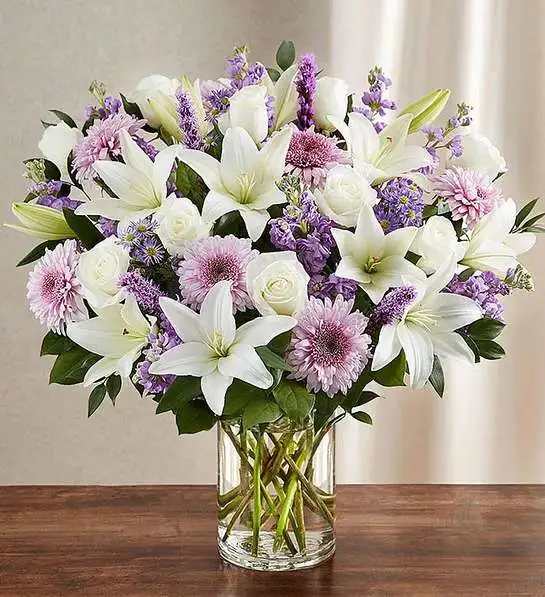 Sincerest Sorrow  Lavender &amp; White - Let a deeply heartfelt sentiment be delivered in true form. Our lush, bountiful bouquet of lavender and white blooms features an elegant mix of roses, lilies and cremones, hand-designed inside a classic clear glass vase. When sent to a service or to the home of family or friends, it makes a genuinely heartwarming gesture.