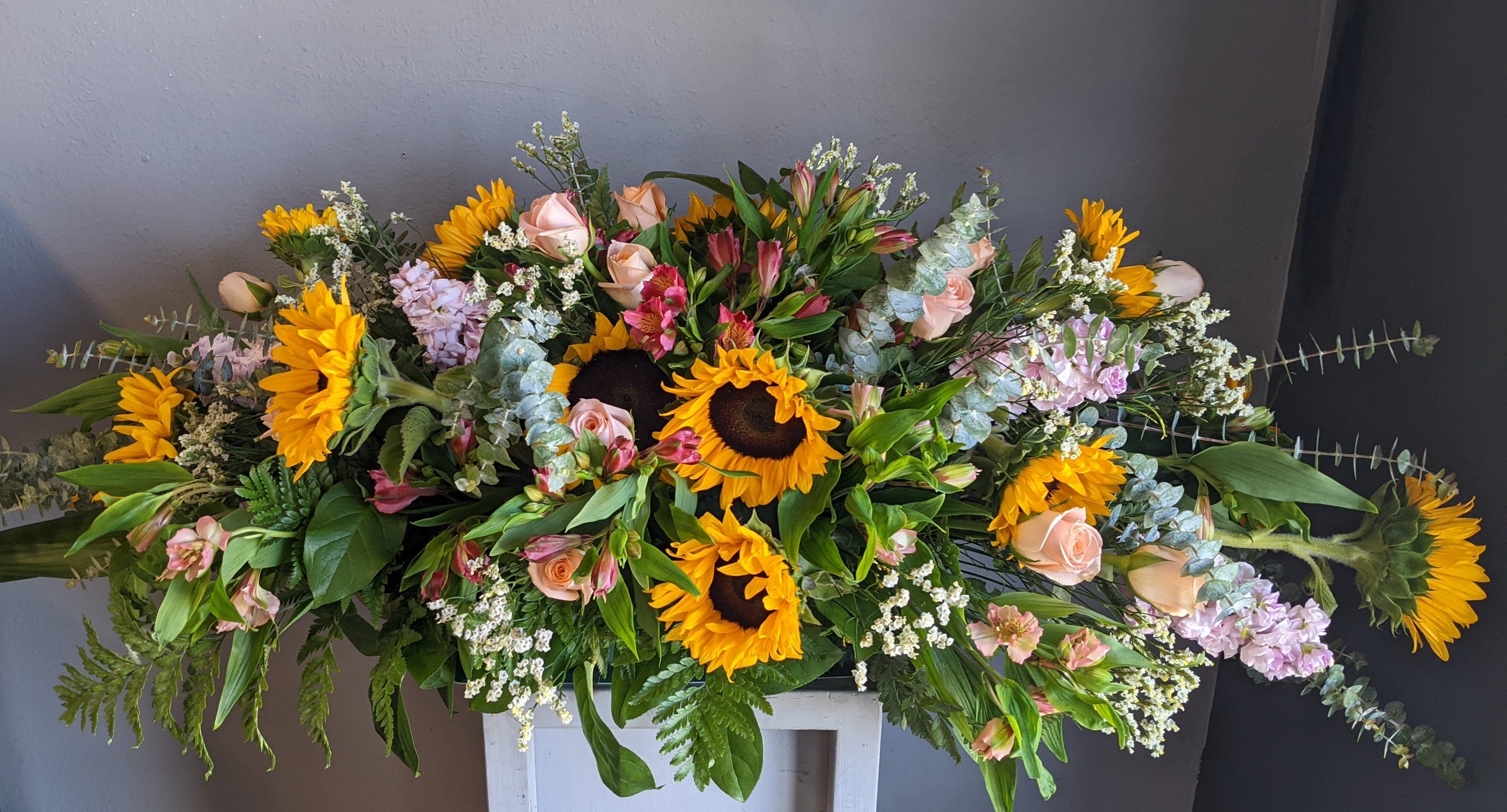 FUNERAL CASKET SPRAY - Field of Dreams 110 - This is a lovely option for a funeral service or church.  This casket can be designed as a half casket or a full casket for either an open casket or a closed casket service. This rustic mix of sunflowers, roses, alstromeria and eucalyptus is a special option to honor the one you've lost.   **This funeral half casket spray can be customized to the color of your choice. The flowers may vary depending on availability of the flowers, special requests and quality of the flowers we have in stock. If you have a special request please add it to our special instruction when placing your order. If you have any questions please don’t hesitate to call. 714 289 1123**