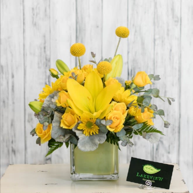Yellow floral arrangement in a square glass vase